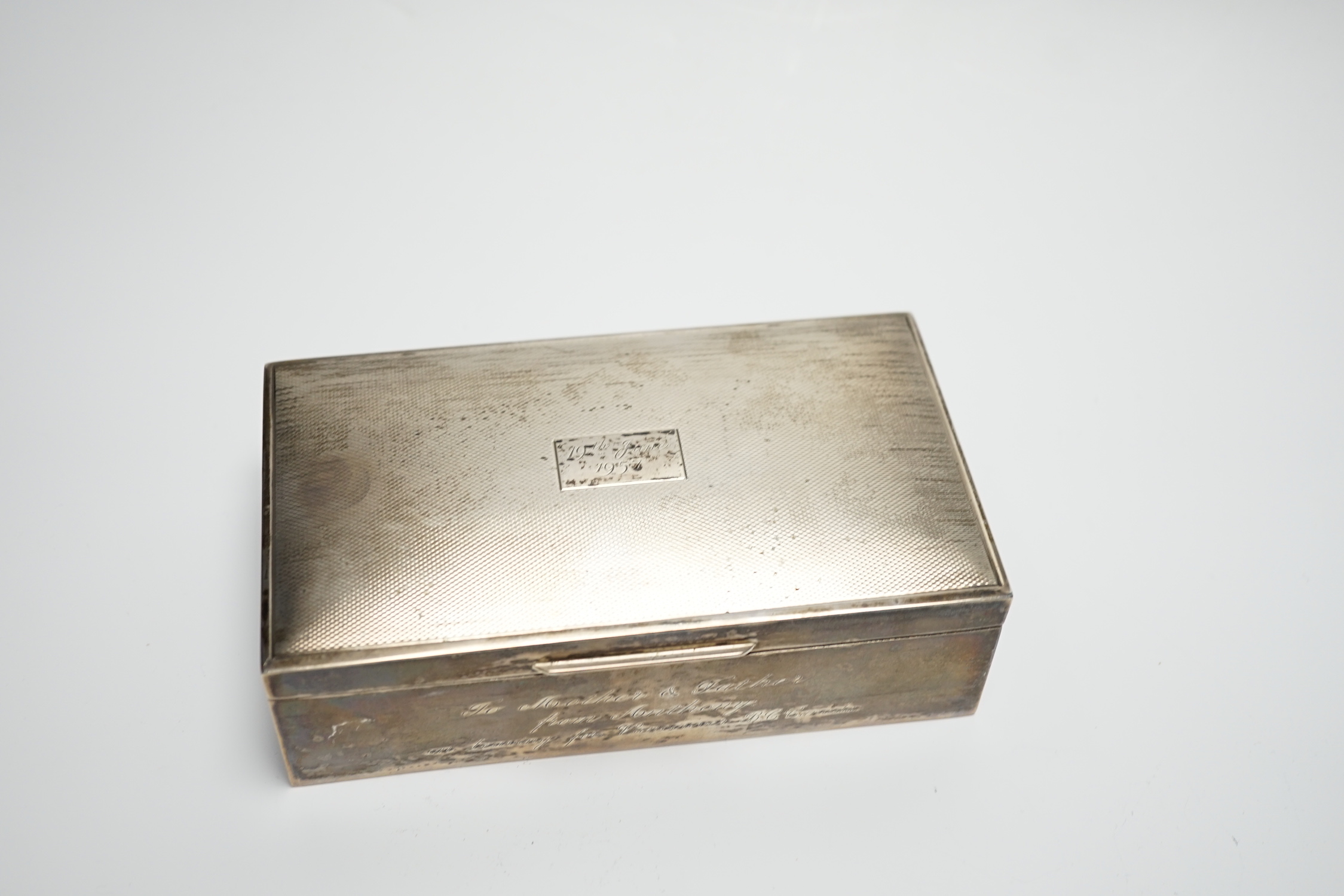 A modern part engine turned silver cigarette box, with engraved inscription, 16cm and a silver serviette ring.